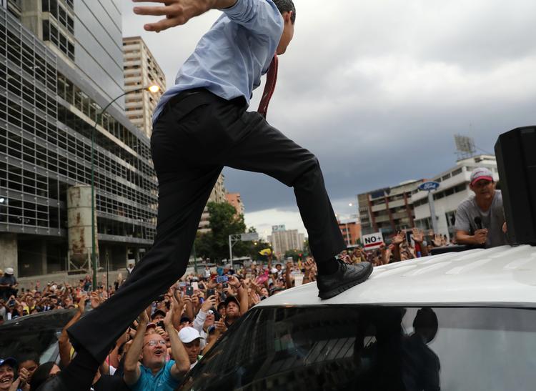 Oppositionsleder og selvudråbt præsident Juan Guaido springer op på en bil for at holde en tale til demonstranter i Caracas. Foto: Stringer/Ritzau Scanpix