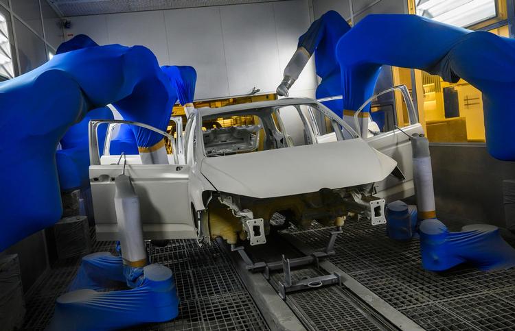 En bilkrop males af robotter på Volkswagens fabrik i Wolfsburg, Tyskland. Bilproducenten skærer ned i medarbejderstaben, oplyser den.   Foto: John Macdougall/Ritzau Scanpix
