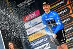 Indehaveren af den første førertrøje i Tirreno-Adriatico australieren Michael Hepburn optræder yderst sjældent ved podieseancerne på landevejen, men han havde ingen problemer med at håndtere flasken med de gyldne dråber. Foto: La Presser - D'Alberto/Ferrari. 