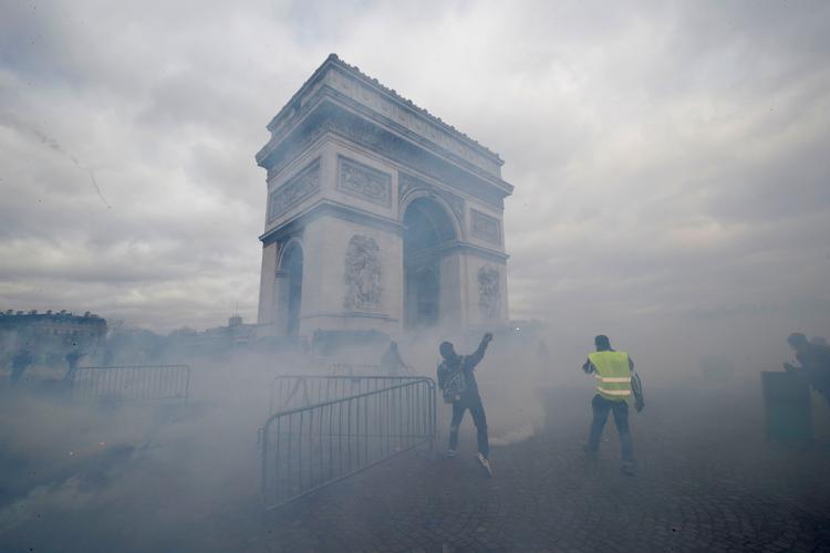 Triumfbuen i Paris blev lørdag indhyllet i røg, da politiet og demonstranter stødte sammen.  Foto: Philippe Wojazer/Ritzau Scanpix