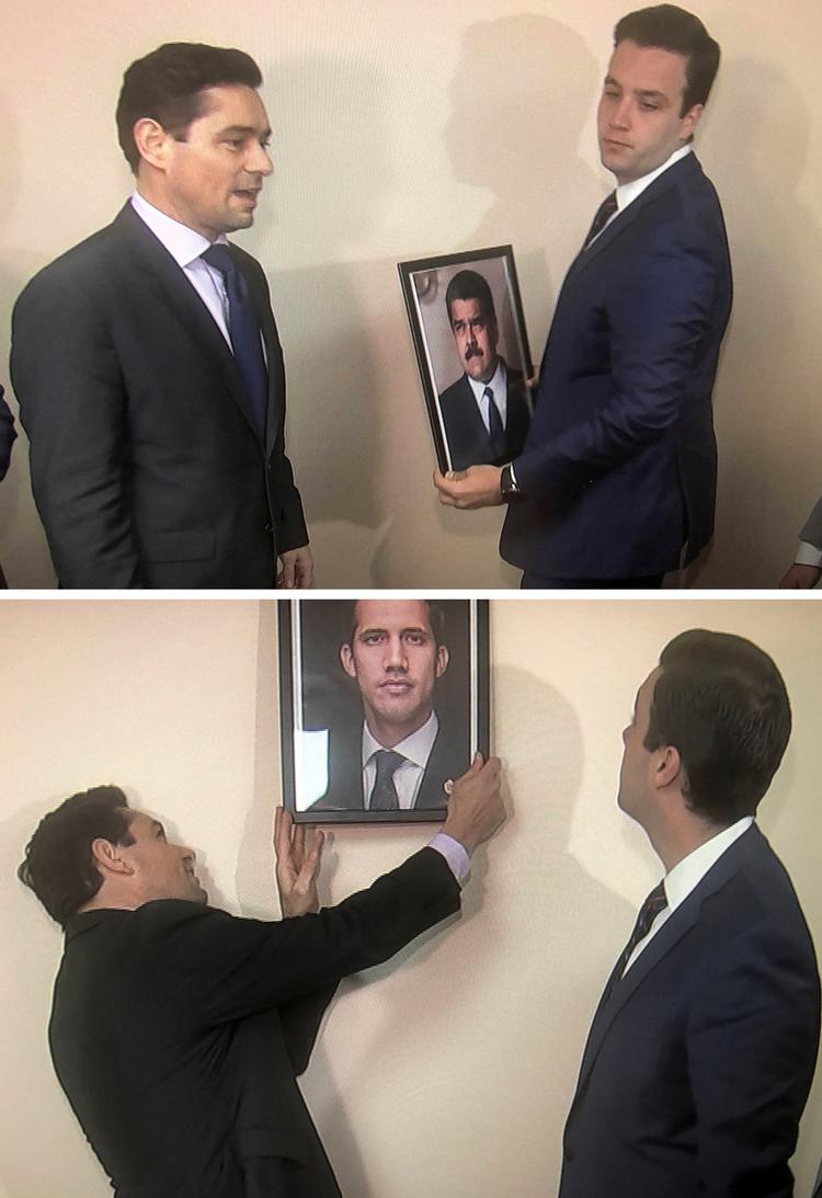 Carlos Vecchio (tv), den særlig udsending i USA og Juan Guaido udskifter et billede af Nicolas Maduro med et tilsvarende portræt af Guaido i Washington, USA.
   Foto: Gershon Peaks/Ritzau Scanpix