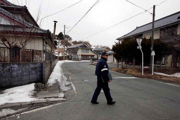 Politibetjent tjekker de ubeboede huse i den forladte by Iitate nordvest for Fukushima-atomkraftværket. Marts 2013.
   Foto: Greg Baker/Ritzau Scanpix