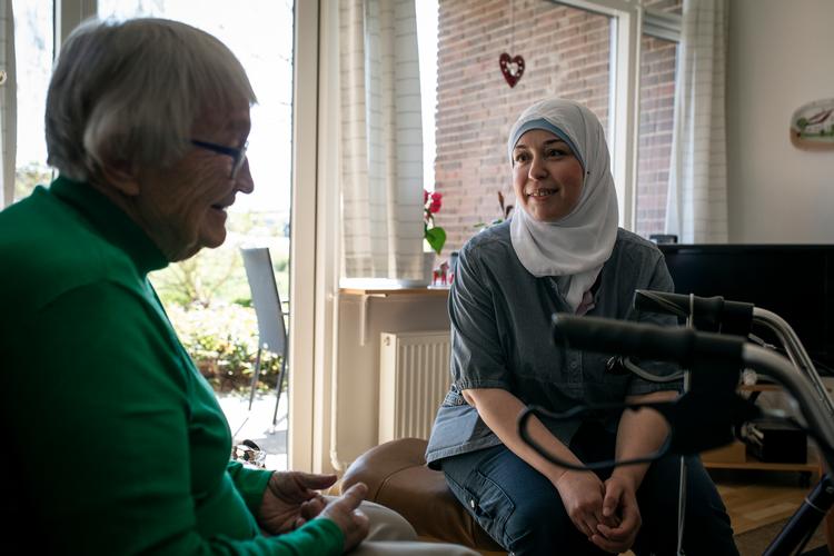 Social- og sundhedsassistent Latifah Adil El-Set sammen med en af beboerne på plejecentret Korsvang, Hanne Himmelstrup:. »Jeg kan  mærke, at de ældre trækker sig eller bliver urolige, fordi vi har mere travlt« Foto: Jens Hartmann Schmidt/POLFOTO