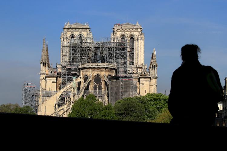 En person betragter Notre Dame, der brændte mandag. Pengene strømmer ind til genopbygningen af den ikoniske kirke. 
   Foto: Gonzalo Fuentes/Ritzau Scanpix
