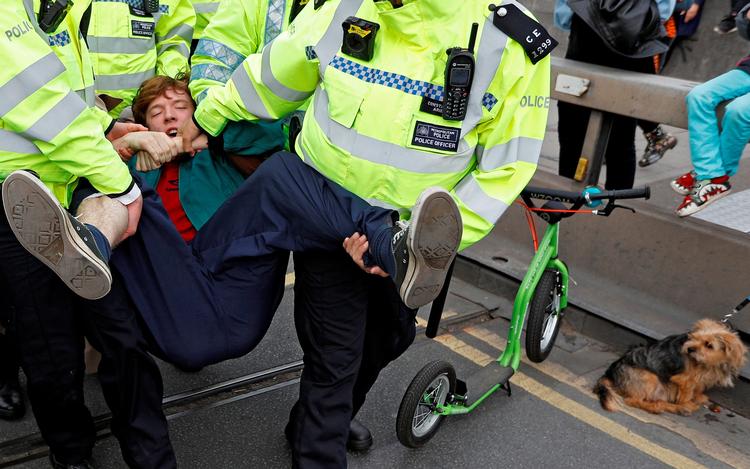 Politibetjente fjerner klimaaktiviester foran Waterloo Bridge under en protest med gruppen Extinction Rebellion. Lørdag planlægges ny aktion i Heathrow lufthavnen.  Foto: Peter Nicholls/Ritzau Scanpix