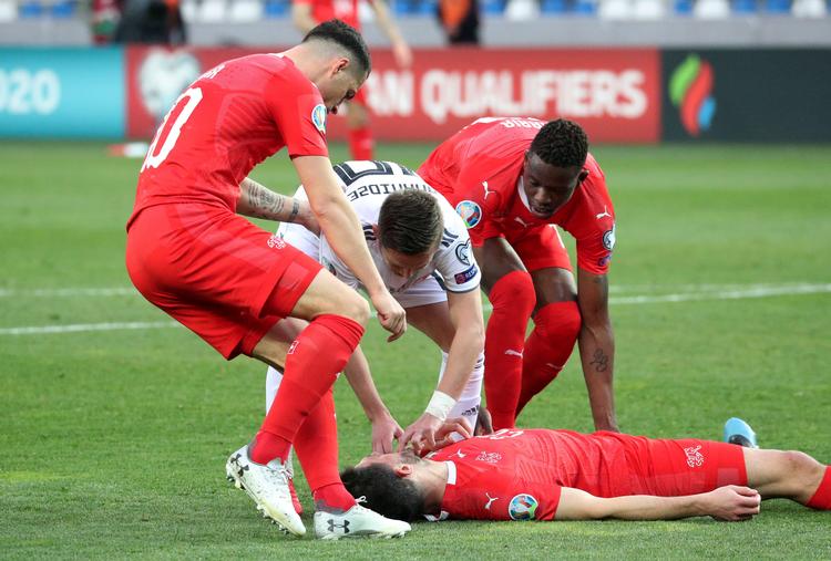 Efter at have stødt hovedet sammen med en modspiller mistede Fabian Schär bevidstheden i Schweiz' landskamp mod Georgien, og med- og modspillere ilede til for at hjælpe ham. Alligevel spillede Schär videre. Foto: Irakli Gedenidze/Ritzau Scanpix