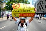 En demonstrant 1. maj i Caracas visre sin utilfredshed med præsident.  Nicolas Maduro.
 Foto: Matias Delacroix/Ritzau Scanpix