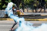 En demonstrant i Caracas smider en molotovcocktail mod sikkerhedsstyrkerne. 
 Foto: Matias Delacroix/Ritzau Scanpix