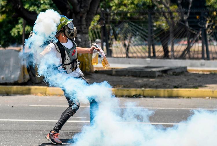 En demonstrant i Caracas smider en molotovcocktail mod sikkerhedsstyrkerne. 
 Foto: Matias Delacroix/Ritzau Scanpix