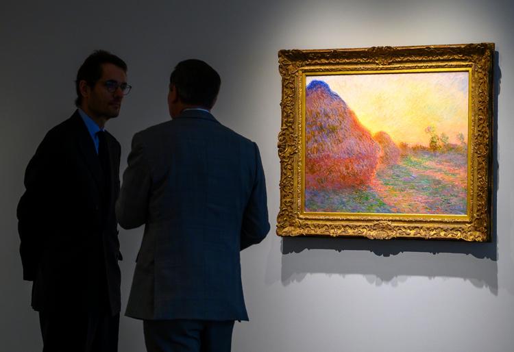 Medarbejdere fra Sotheby's står ved Monet-billedet 'Meules'. Det blev solgt for cirka 736 kroner.  Foto: Don Emmert/Ritzau Scanpix