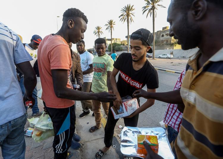 En libysk mand uddeler mad og juice til arbejdere i Libyens hovedstad, Tripoli. Vandforsyningen til hovedstaden er lukket af en bevæbnet gruppe. Og det kan ramme millioner af mennesker.  Foto: Mahmud Turkia/Ritzau Scanpix
