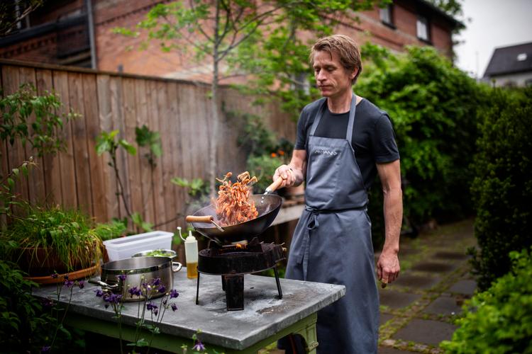 Adam Aamann tilbereder fjordrejer over bål i haven.  Foto: Miriam Dalsgaard/POLFOTO