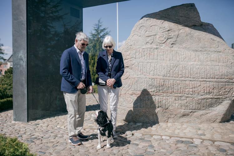 Mads og Elin Drangsfeldt og hunden Hannibal, alle fra Vojens, foran Harald Blåtands runesten i Jelling, der blev starten på det Danmark, vi kender. 
   Foto: Jens Hartmann Schmidt/POLFOTO
