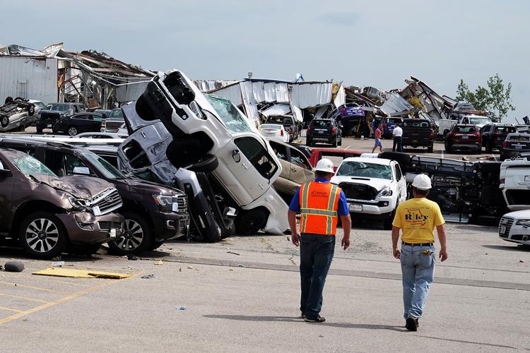 Arbejdere passerer ødelagte trucks hos i Toyota forhandler i byen Jefferson City i  Missouri. Tornadoerne har bragt megen ødelæggelse med sig.   Foto: Carlo Allegri/Ritzau Scanpix