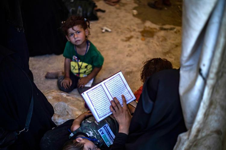 
   Al-Hol-lejren huser både IS-krigsfanger og almindelige internt fordrevne flygtninge fra Syrien og Irak. Her venter en gruppe syriske kvinder og børn på at blive sendt hjem til Syrien - og læser i koranen imens. 
   Foto: Delil Souleiman/Ritzau Scanpix