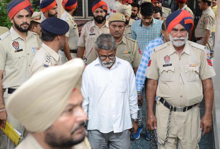 
  Arkivfoto:  Indisk politi eskorter præsten Sanji Ram (i midten) ud af retten i Kashmir i juni. Sanji Rami er en af de tre, som nu har fået  livstid på grund af forbrydelsen.  (Photo by NARINDER NANU / AFP)
   Foto: Narinder Nanu/Ritzau Scanpix