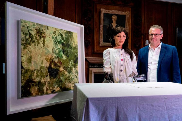 Galleridirektør og opfinder Aidan Meller (ham til højre) præsenterer Ai-Da og et oliemaleri.   Foto: Niklas Halle'n/Ritzau Scanpix