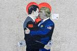 Her ses vægmaleriet 'Smart Love' af den italienske gadekunstner TvBoy. Det er udstillet på en væg i Milan og forestiller den kinesiske og den amerikanske præsident, der holder om hinanden og kysser. I hænderne har de henholdsvis en iPhone og en Huawei smartphone som symbol på forening. Foto: Miguel Medina/Ritzau Scanpix