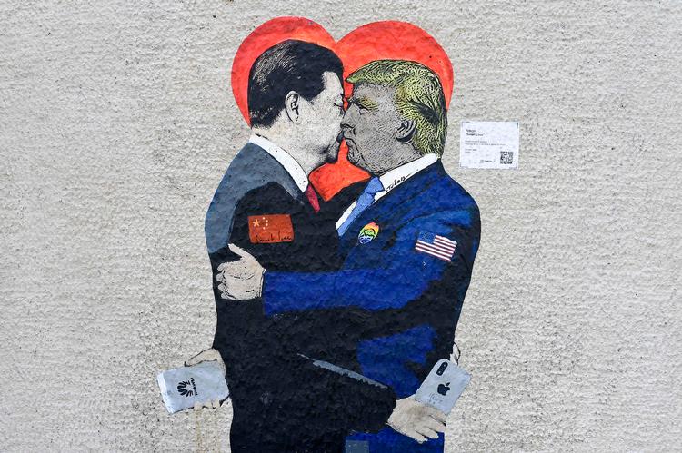 Her ses vægmaleriet 'Smart Love' af den italienske gadekunstner TvBoy. Det er udstillet på en væg i Milan og forestiller den kinesiske og den amerikanske præsident, der holder om hinanden og kysser. I hænderne har de henholdsvis en iPhone og en Huawei smartphone som symbol på forening. Foto: Miguel Medina/Ritzau Scanpix