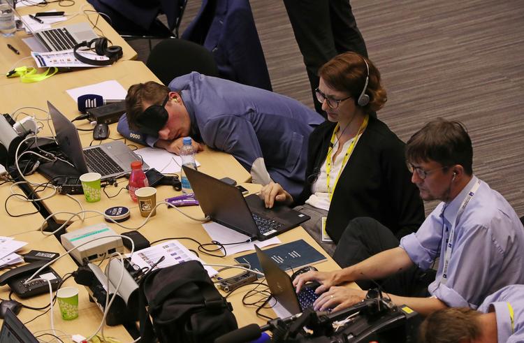 En journalist tager en lur efter at have ventet hele natten på, at EU's stats- og regeringsledere skulle indgå en aftale.  Foto: Yves Herman/Ritzau Scanpix