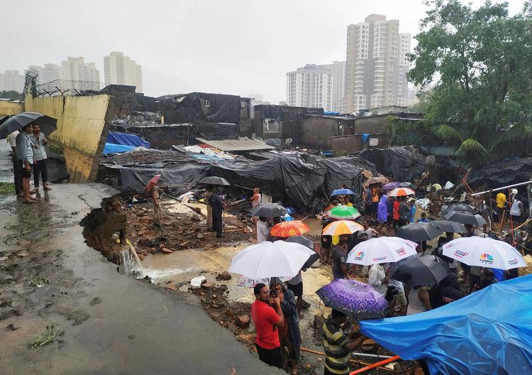 Folk står ved siden af den kollapsede mur i Mumbai, Indien.  Foto: Prashant Waydande/Ritzau Scanpix