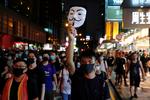 En demonstrant holder en Guy Fawkes-maske, der anses som et symbol for oprør, i vejret, mens han går igennem Hongkongs turistdistrikt, Nathan Road søndag.  Foto: Tyrone Siu/Ritzau Scanpix