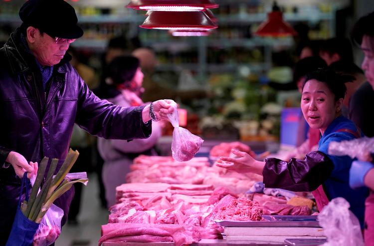 En handlende får overbragt svin fra en sælger på et marked i Beijing. Landet fremviser sløjeste vækst i årtier. Foto: Jason Lee/Ritzau Scanpix