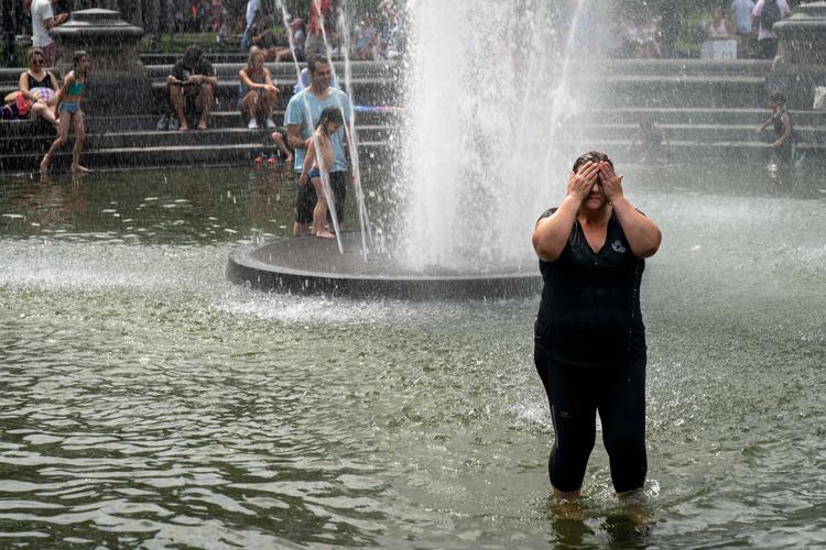 Kvinde køler ned i Washington Square Park i New York City, mens smeltende hede bevæger sig ind over landet og ventes at ramme i weekenden.  Foto: Drew Angerer/Ritzau Scanpix