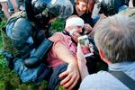 En demonstrant, der er kommet til skade under lørdagens demonstration i Moskva, hvor omkring 1.000 blev anholdt, og et medlem af Nationalgarden i kampudstyr Foto: Maxim Zmeyev/Ritzau Scanpix