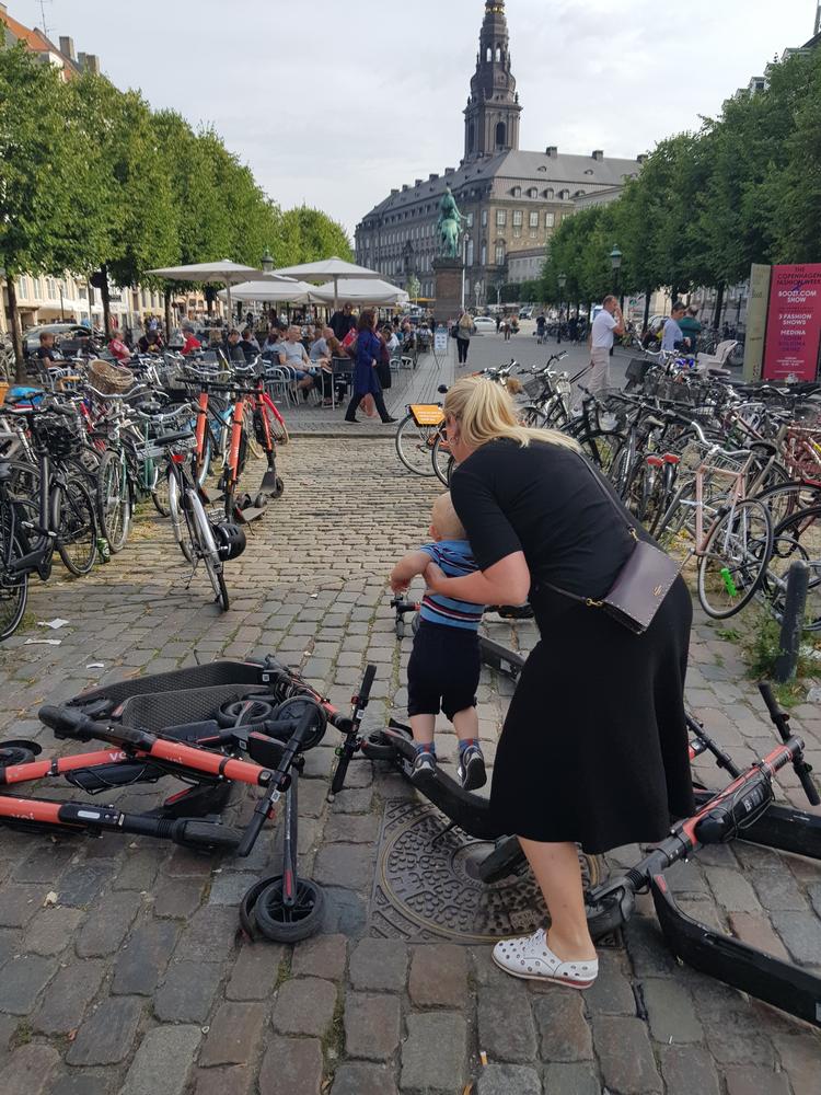 En kvinde forsøger at løfte et barn over væltede løbehjul på Højbro Plads. Foto: Rasmus Klinck, privatfoto