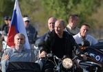 Ruslands præsident kommer kørende på motorcykel med den siddende guvernør i Sevastopol, Mikhail Razvozhayev, og lederen af Krim, Sergei Aksyonov.
  Foto: Sputnik/Ritzau Scanpix