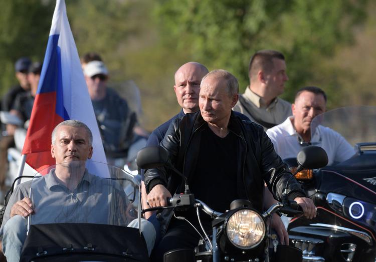 Ruslands præsident kommer kørende på motorcykel med den siddende guvernør i Sevastopol, Mikhail Razvozhayev, og lederen af Krim, Sergei Aksyonov.
  Foto: Sputnik/Ritzau Scanpix