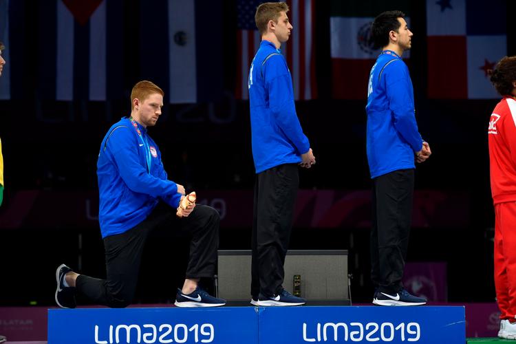 
 Nick Itkin og Gerek Meinhardt stod op under sejrsceremonien efter det amerikanske holds sejr i kårdekonkurrencen, knælede Race Imboden. Foto: Jose Sotomayor - Lima 2019/Ritzau Scanpix