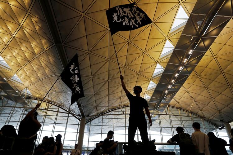 Som en tydelig advarsel til demonstrationerne har kinesiske statsmedier det seneste døgn bragt artikler om den massive oprustning af politistyrker langs grænsen til Hongkong. På billedet ses demonstranter med flag, der bærer teksten »Befri Hongkong. Vor tids revolution«. Foto: Tyrone Siu/Ritzau Scanpix