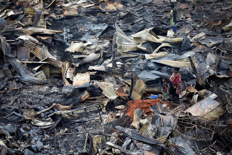 Lokale beser det område i Dhaka, de bor i, efter en voldsom brand hen over weekenden har hærget.
     Foto: Mohammad Ponir Hossain/Ritzau Scanpix
