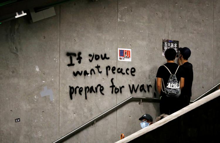 Demonstranter står ved siden af et klart budskab skrevet på en væg i Hongkong. Kina står bag kampagne, der bevidst spreder politisk uorden i Hongkong, skriver Twitter på blog. Foto: Kim Hong-ji/Ritzau Scanpix