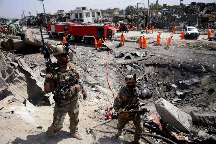 Afghanske sikkerhedsstyrker holder vagt, mens oprydningsholdet samler sig på det sted i Kabul, hvor en voldsom eksplosion dræbte 16 personer.  Foto: Str/Ritzau Scanpix