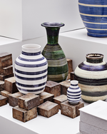 Tulle Emborg, en af Kähler-værkstedets dygtigste kvindelige malerdamer i 1930’erne og 1940’erne, skabte det stribede design på vaserne bagerst i billedet, der blev fortolket og bragt til live igen af designerduoen Stilleben i Omaggio-vasen i 2007.  Foto: Kähler