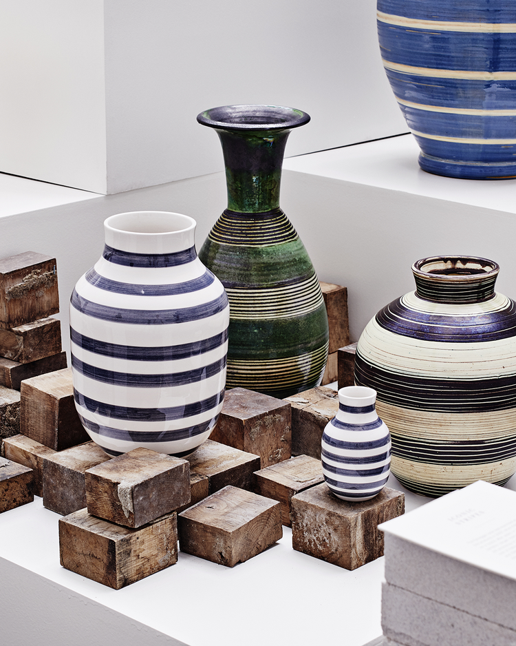 Tulle Emborg, en af Kähler-værkstedets dygtigste kvindelige malerdamer i 1930’erne og 1940’erne, skabte det stribede design på vaserne bagerst i billedet, der blev fortolket og bragt til live igen af designerduoen Stilleben i Omaggio-vasen i 2007.  Foto: Kähler