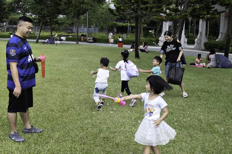 Forældre leger med deres børn i en park i Hongkong en lørdag eftermiddag, samtidig med at der er protester i et andet kvarter nogle få metrostop væk. Foto: Claus Blok Thomsen