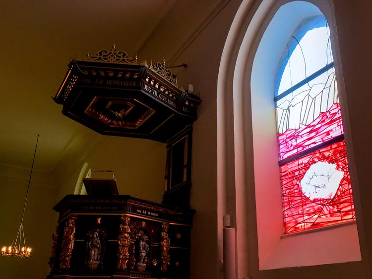En begravelse er lettere at bære, hvis næste generation står klar til at tage over. Det hjælper også med et lyserødt skær fra Per Kirkebys vinduer i Gentofte Kirke. Foto: Per Munch