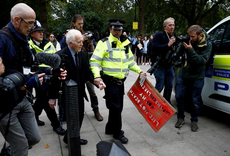 Politiet anholder her 83-råige Phil Kingston, som sprayede et klima-slogan på en mur i London.  Foto: Henry Nicholls/Ritzau Scanpix