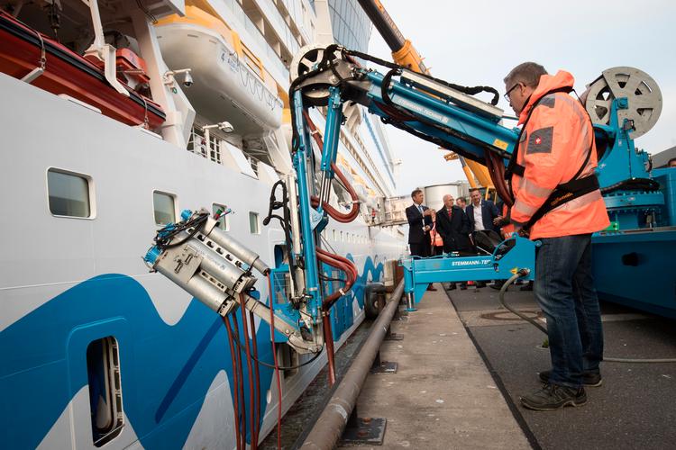 En tekniker styrer strømstikket hen til krydstogtskibet 'Aidasol', så det kan modtage landstrøm i Hamburgs havn. Strømmen, som også kaldes 'Cold Ironing' eller on shore power, skåner både miljøet for sundhedsskadelig røg og klimaet, fordi strøm er langt mindre CO2-belastende end en skibsmotor.    Foto: Christian Charisius/Ritzau Scanpix