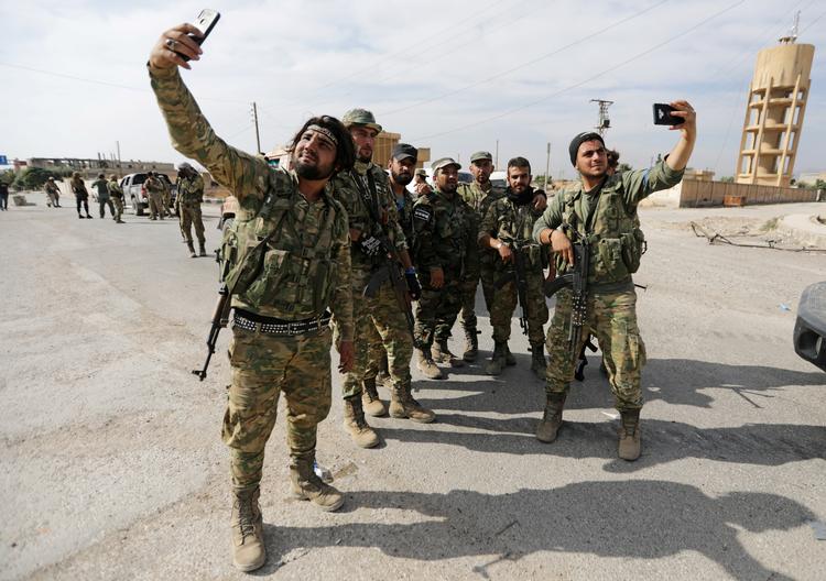 Nu er vi her. En gruppe af de tyrkisk støttede syriske krigere tog selfies, da de kom til udkanten af grænsebyen Tel Abyad for at rykke frem mod kurderne. Foto: Khalil Ashawi/Ritzau Scanpix