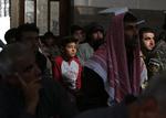 Muslimer til fredagsbøn dagen efter våbenhvilen er gået i gang i den syriske by Tal Abyad. Flaget på uniformen til højre bruges af den tyrkisk finansierede Frie Syriske Hær og den oprørske Frie Syriske Hær, selvom de ikke har noget med hinanden at gøre. Foto: Bakr Alkasem/Ritzau Scanpix