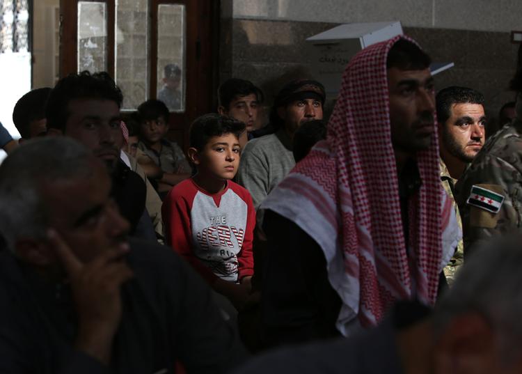 Muslimer til fredagsbøn dagen efter våbenhvilen er gået i gang i den syriske by Tal Abyad. Flaget på uniformen til højre bruges af den tyrkisk finansierede Frie Syriske Hær og den oprørske Frie Syriske Hær, selvom de ikke har noget med hinanden at gøre. Foto: Bakr Alkasem/Ritzau Scanpix