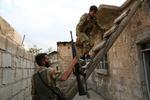 Tyrkisk-støttede syriske soldater klatrer op på taget af et hus i den syriske grænse. En tyrkisk soldat er angiveligt søndag blevet dræbt af kurdiske styrker i den nordøstlige del af Syrien. Foto: Nazeer Al-khatib/Ritzau Scanpix