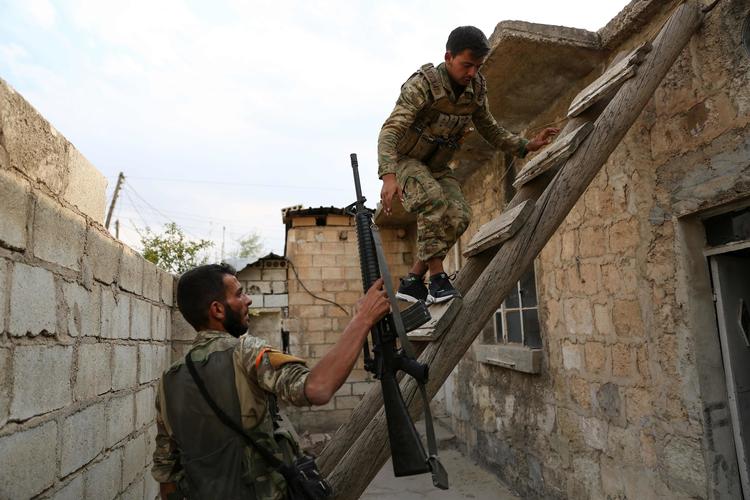 Tyrkisk-støttede syriske soldater klatrer op på taget af et hus i den syriske grænse. En tyrkisk soldat er angiveligt søndag blevet dræbt af kurdiske styrker i den nordøstlige del af Syrien. Foto: Nazeer Al-khatib/Ritzau Scanpix