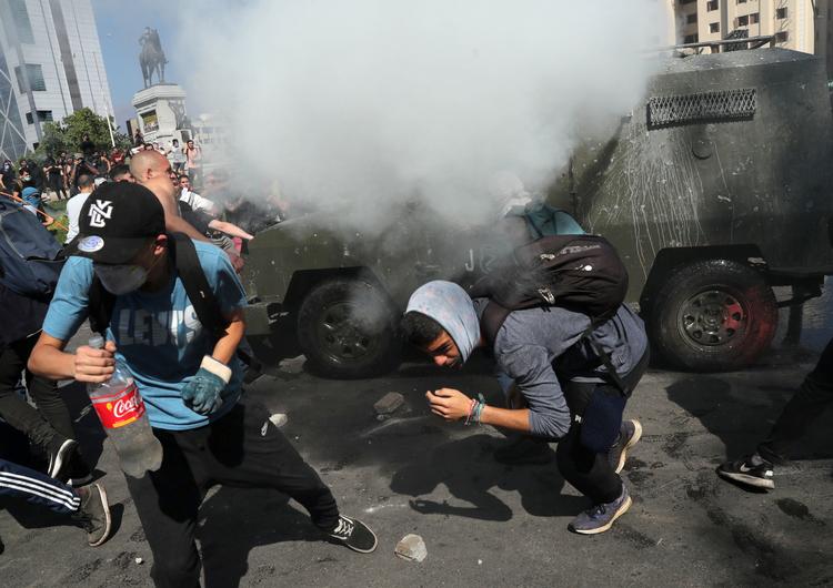 Demonstranter flygter fra tåregas under protester i Chiles hovedstad Santiago.  Foto: Ivan Alvarado/Ritzau Scanpix
