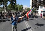 En demonstrant flager med det chilenske flag foran soldater.  

   Foto: Ivan Alvarado/Ritzau Scanpix